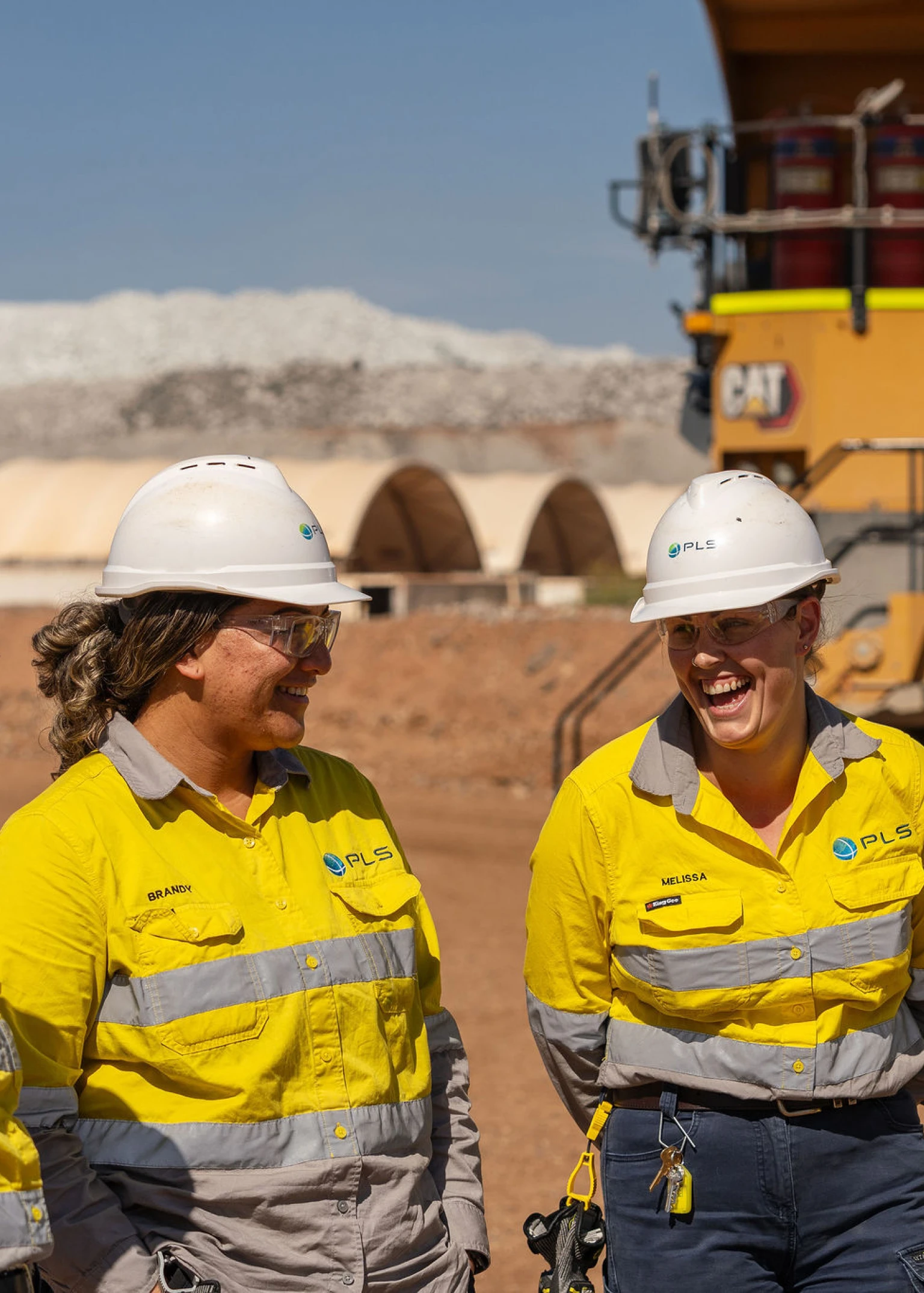 Four PLS employees standing in front of a dump truck at the Pilgangoora Operation